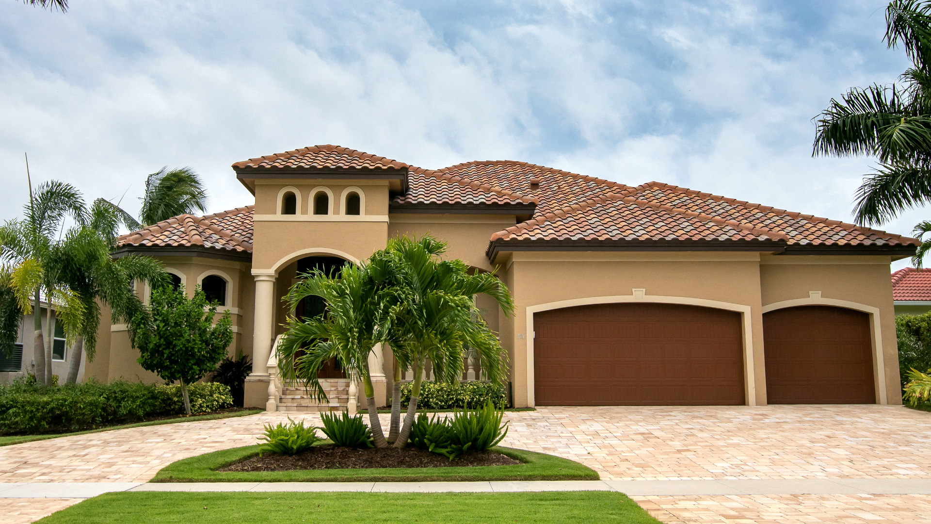 Frontansicht eines großzügigen Hauses in Südwest-Florida mit Doppelgarage und Torbögen